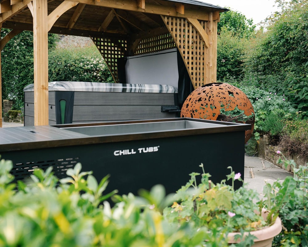 Luxury outdoor cold plunge by Chill Tubs with a cover, set in a lush garden with greenery