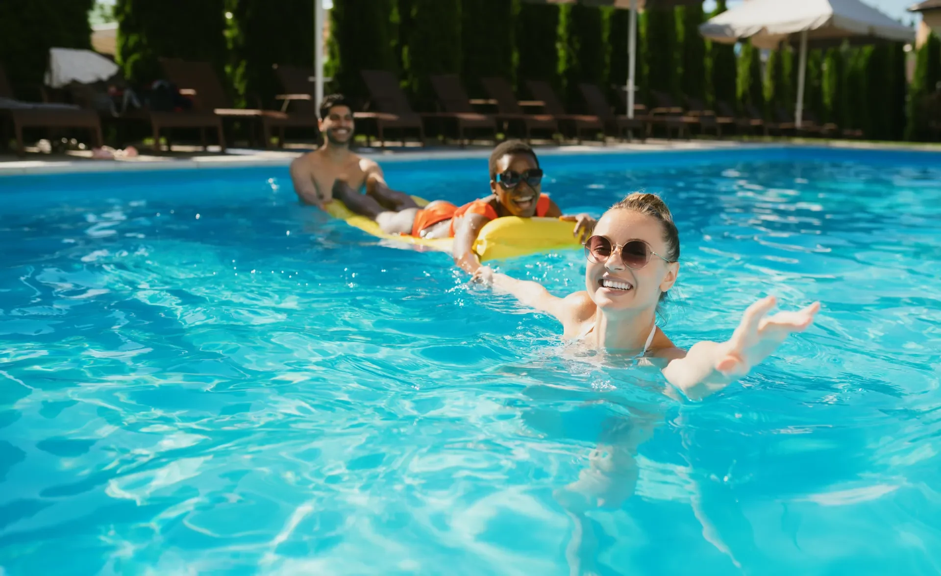 cheerful friends swim on a mattress in the pool 1